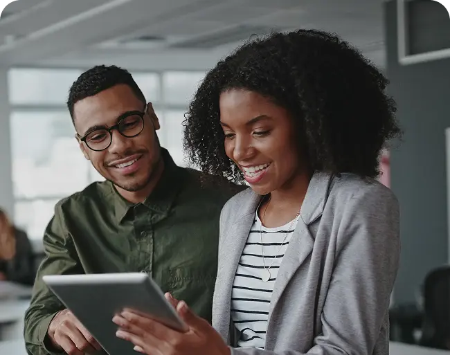 Two professionals engaging with a tablet in a modern office setting, illustrating collaboration and digital marketing strategies for rehab centers.