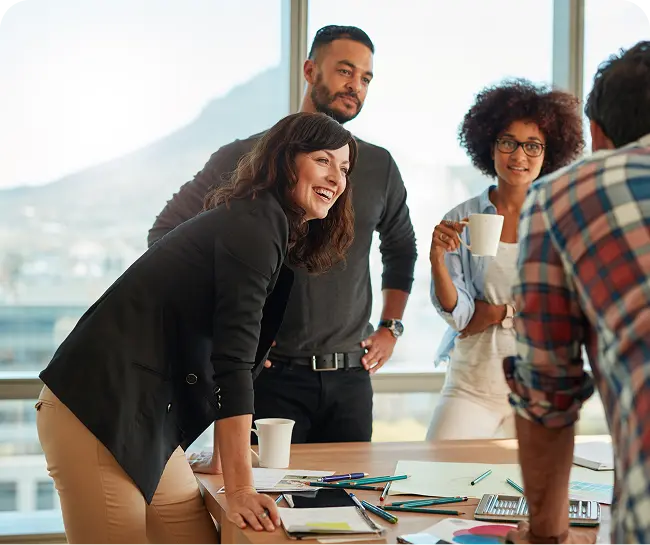 Group of diverse professionals collaborating in a bright office, discussing strategies for recovery center marketing, with notes and coffee cups on the table.