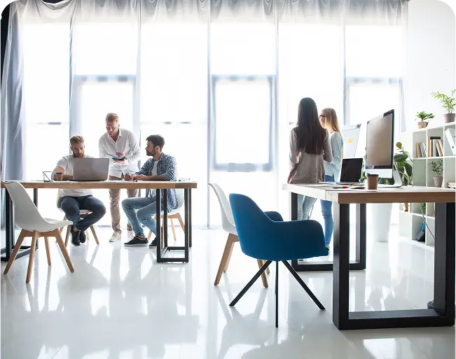 Group of professionals collaborating in a bright, modern office space, discussing strategies for digital marketing and SEO for rehab centers.